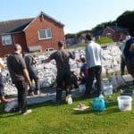 FIDEO: Gweithwyr dan hyfforddiant yn mynd i’r afael â morter calch