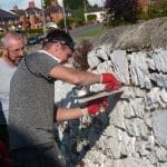 FIDEO: Gweithwyr dan hyfforddiant yn mynd i’r afael â morter calch
