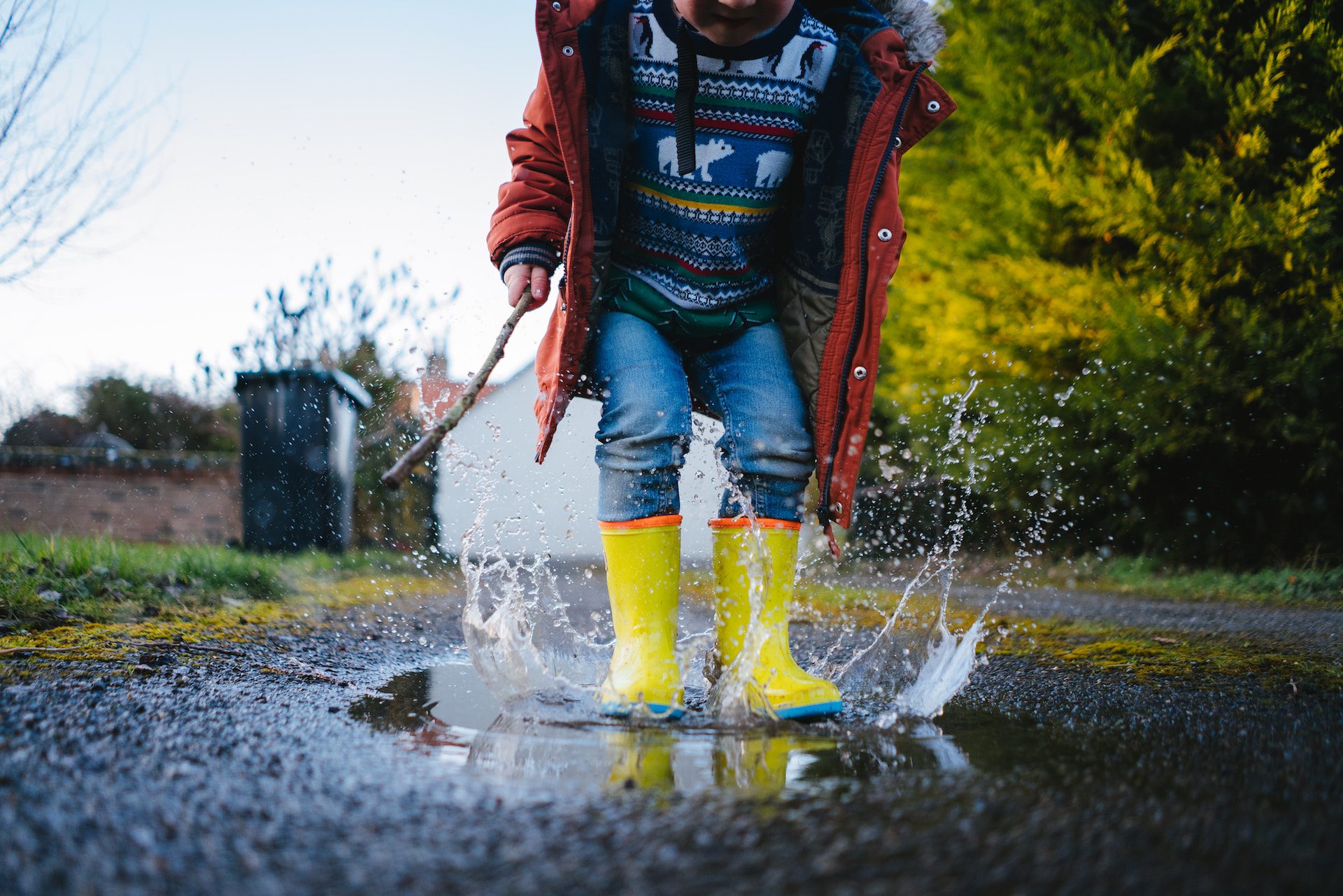 A picture of a young child enjoying jupingin muddy puddles.