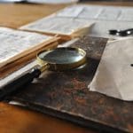 Magnifying glass on top of a file surrounded by sheets of paper