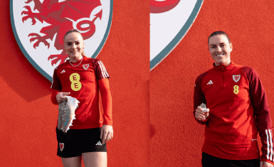Wales Women players, Lily Woodham and Gemma Evans standing in front ofa red background withe FAW dragon logo on it, holidng the boots and the tooth they have donated to the museum.