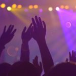 Pobl yn codi eu dwylo mewn cynulleidfa gig cerddoriaeth