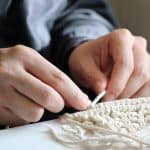 Dwylo oedolyn sy'n dysgu sut i wneud crefftau Macrame